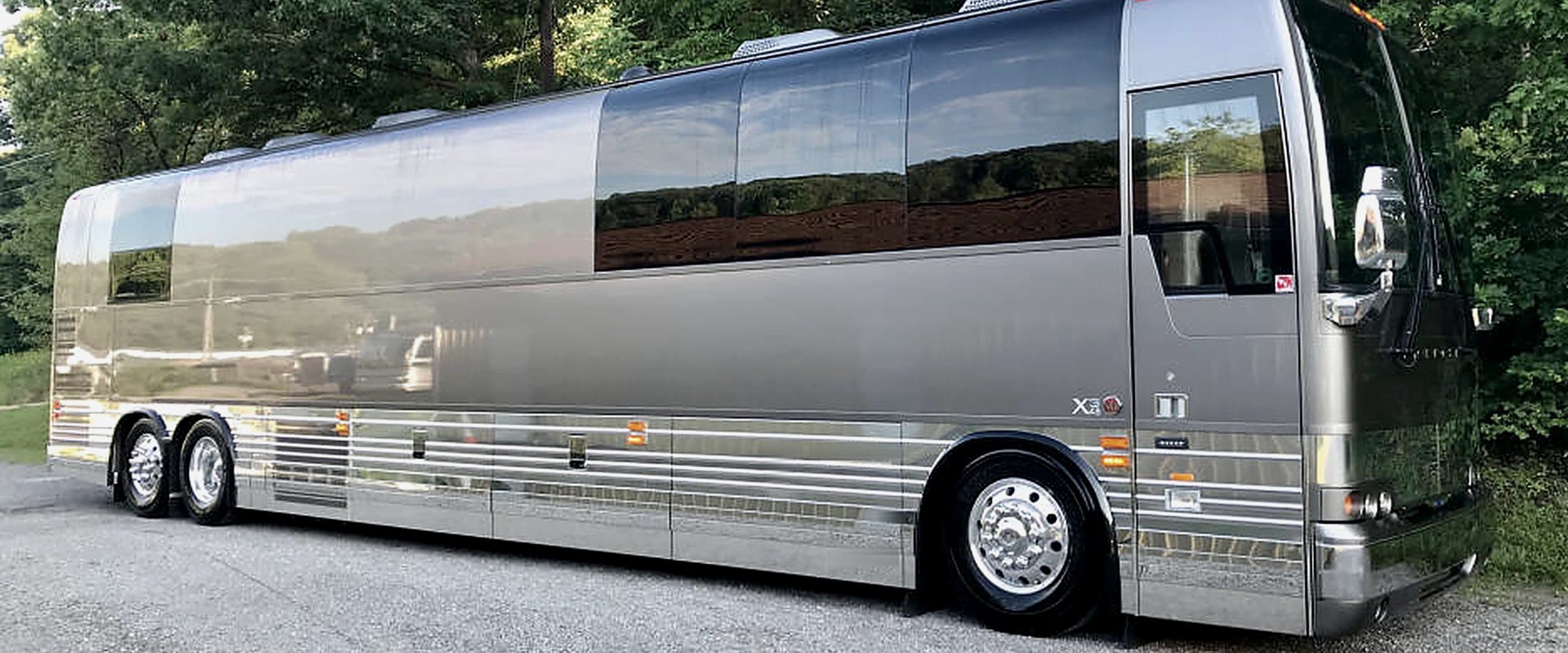 A luxury entertainer coach parked on a tree-lined lot